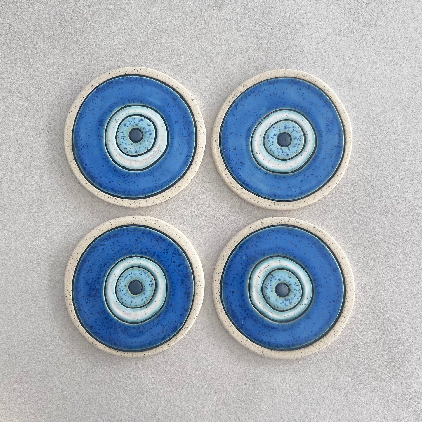 Four Evil Eye ceramic coasters with bare clay rims