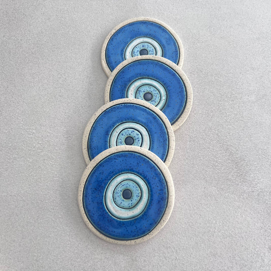 Four Evil Eye ceramic coasters with bare clay rims
