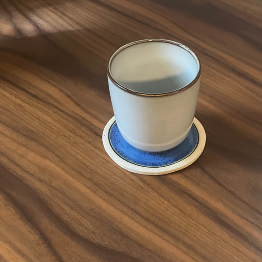 Cup on Evil Eye coaster on a surface
